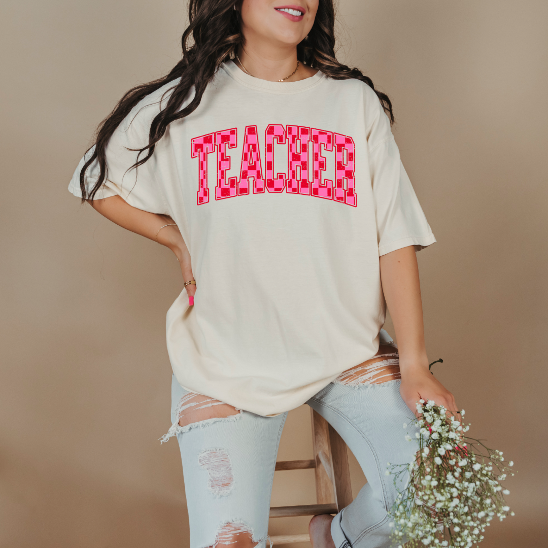 Customized Adult Ivory Graphic tee with pink and red checkered teacher varsity font.