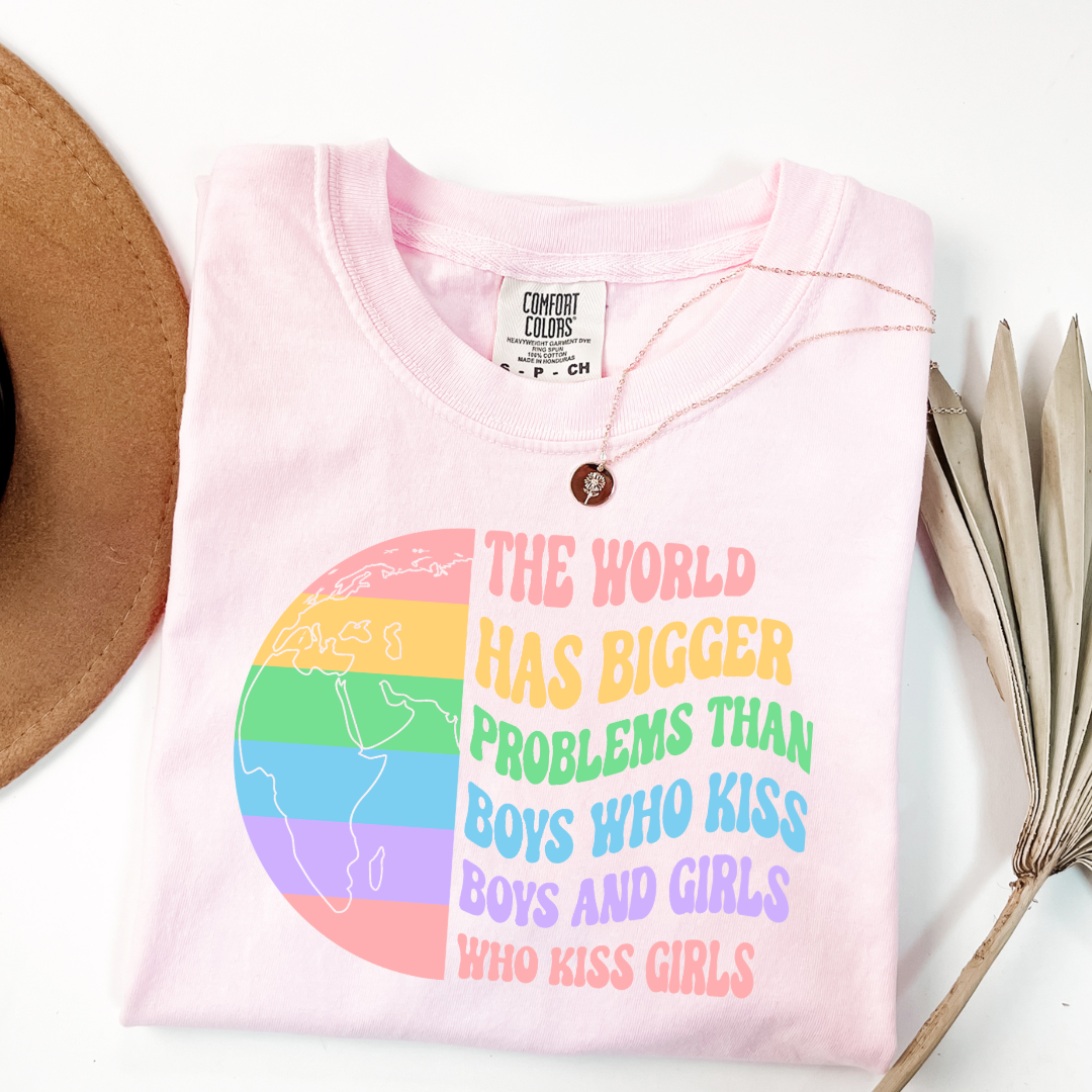 Customized Adult comfort colors Blossom Pink Graphic tee. Split image rainbow world map on one side and quote " the world has bigger problems than boys who kiss boys. and girls who kiss girls" on the other matching adult crewnecks and hoodies available. Perfect for Pride month,
