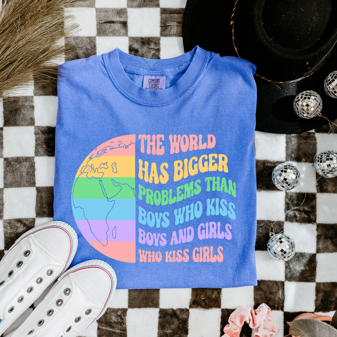 Customized Adult comfort colorsFlo blue Graphic tee. Split image rainbow world map on one side and quote " the world has bigger problems than boys who kiss boys. and girls who kiss girls" on the other matching adult crewnecks and hoodies available. Perfect for Pride month,