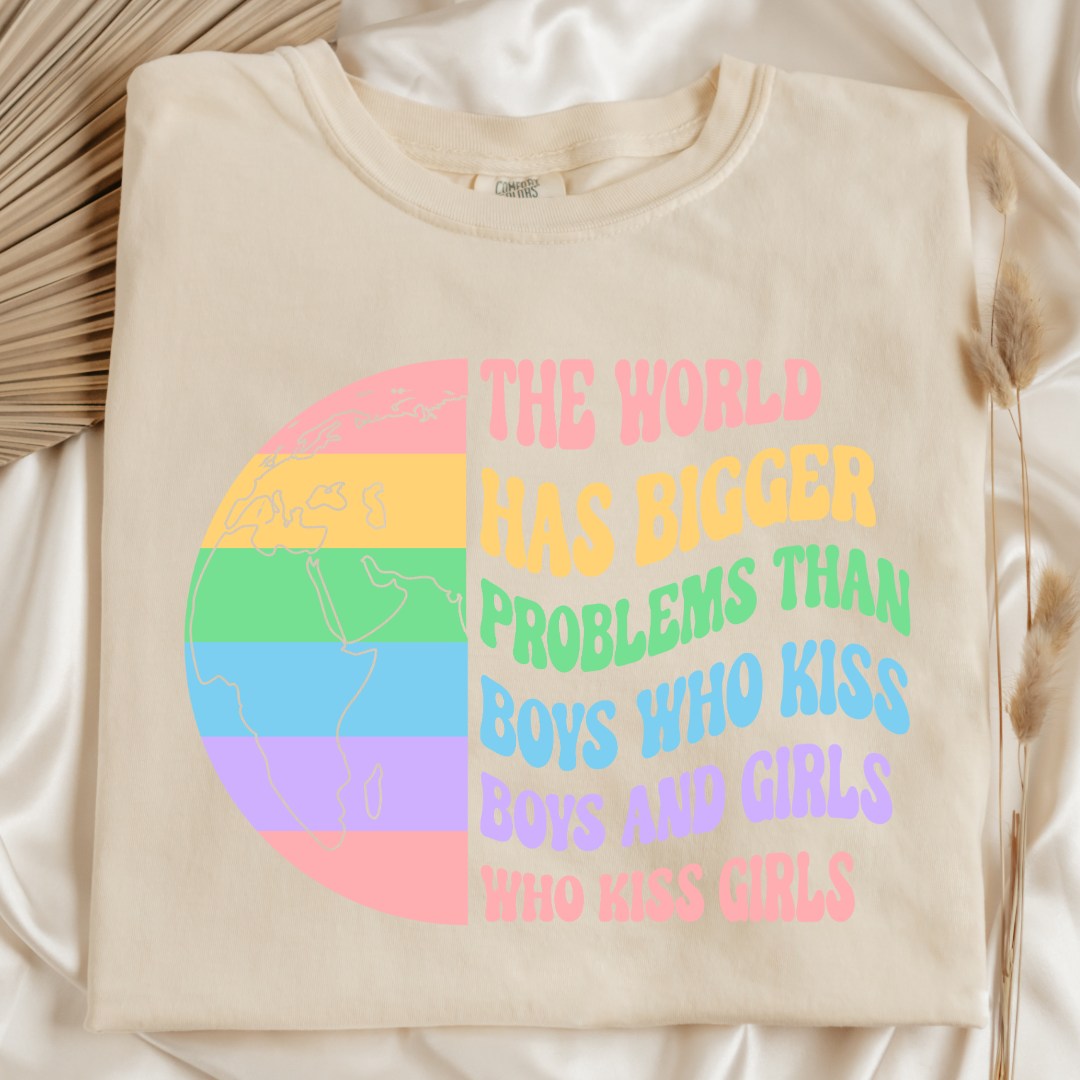 Customized Adult comfort colors Ivory Folded Flat lay Graphic tee. Split image rainbow world map on one side and quote " the world has bigger problems than boys who kiss boys. and girls who kiss girls" on the other matching adult crewnecks and hoodies available. Perfect for Pride month,