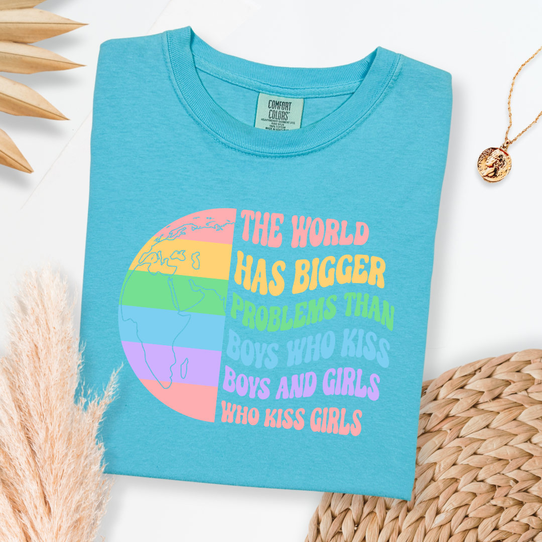 Customized Adult comfort colors Lagoon blue Graphic tee. Split image rainbow world map on one side and quote " the world has bigger problems than boys who kiss boys. and girls who kiss girls" on the other matching adult crewnecks and hoodies available. Perfect for Pride month,