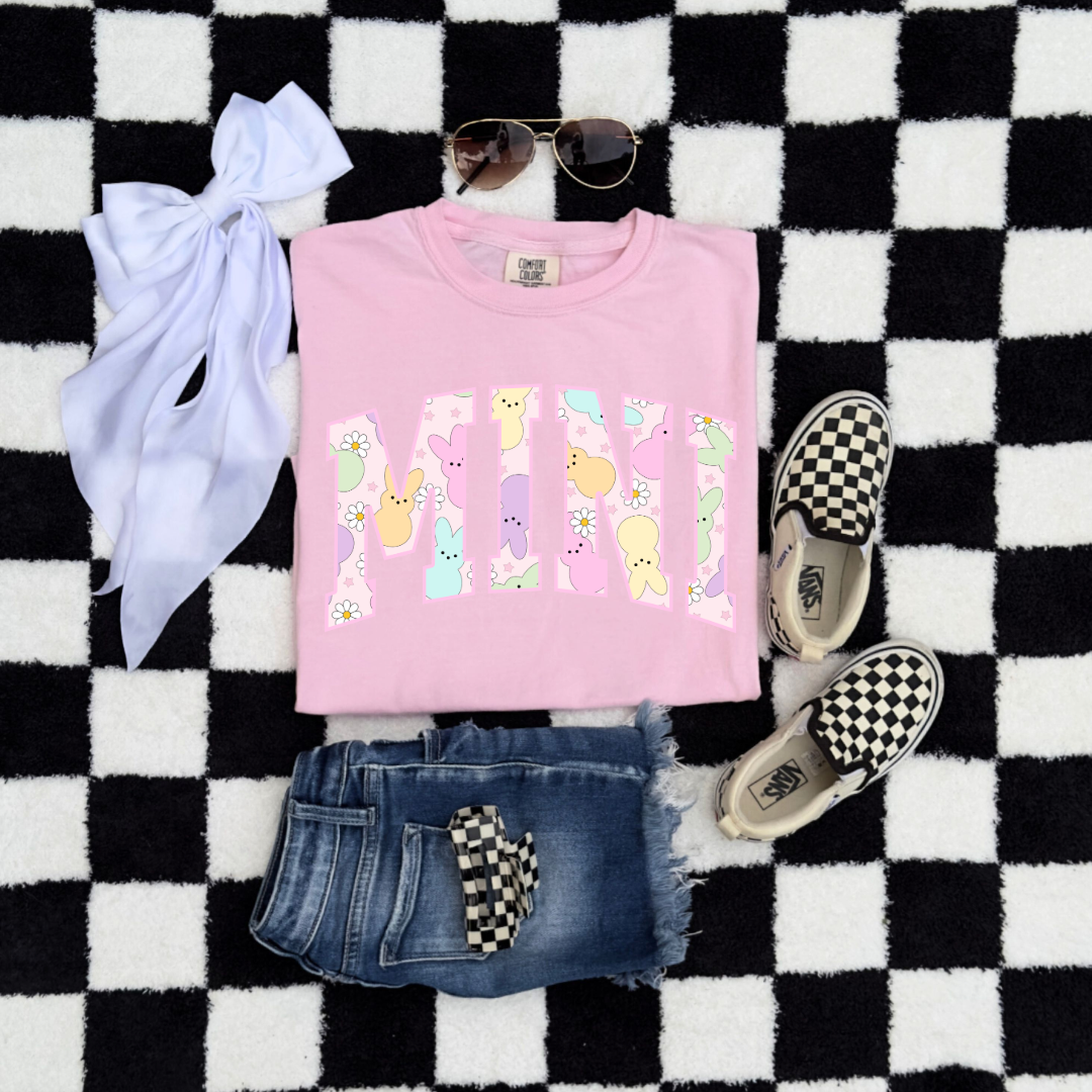 Customized youth mini of a mama and mini matching set varsity lettering with Patel peeps on the inside of the lettering matching youth crew available comfort colors blossom pink graphic tee flat lay