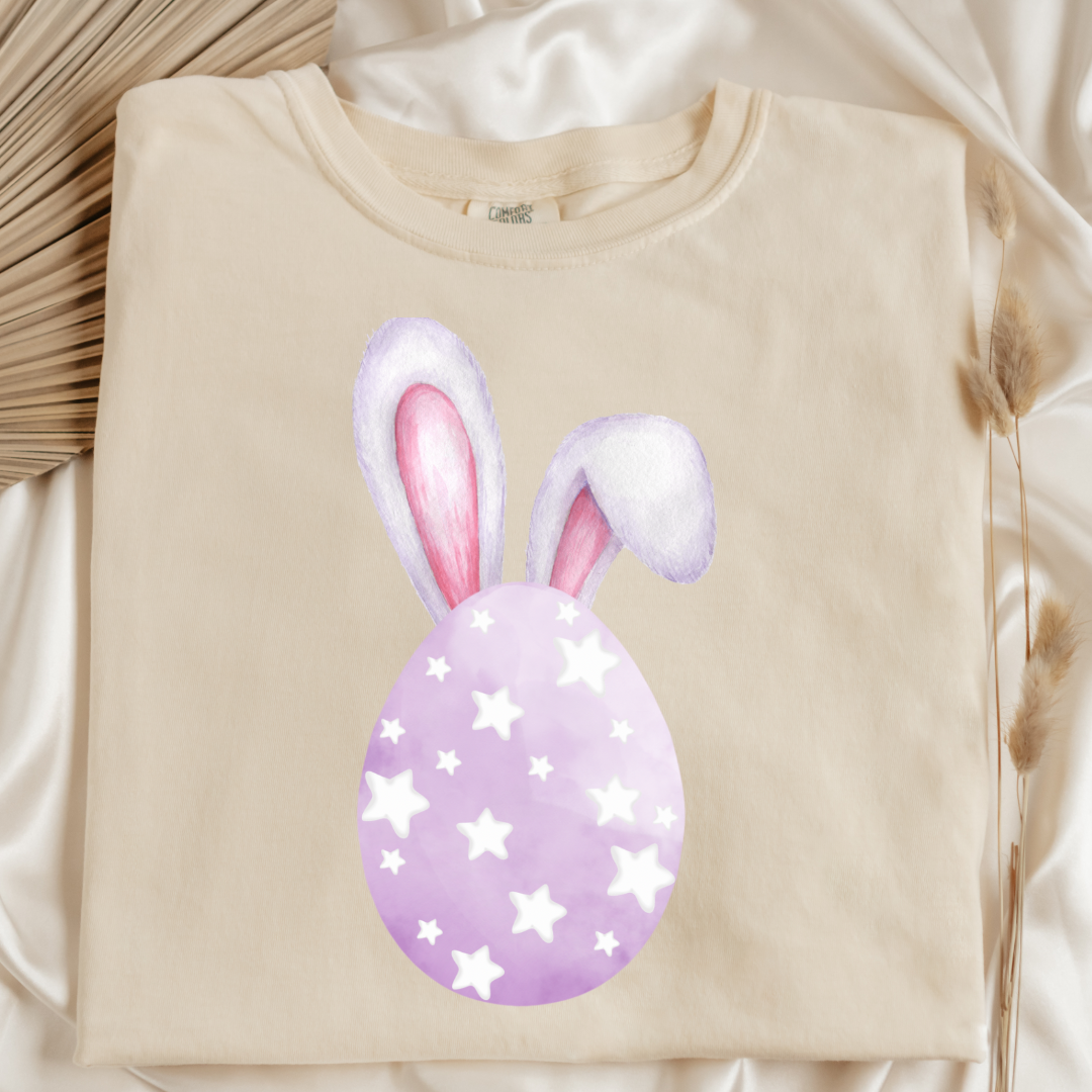 Customized adult comfort colors ivory flat lay graphic tee with purple watercolor egg with white stars matching crewneck and hoodies available in youth and adult sizes