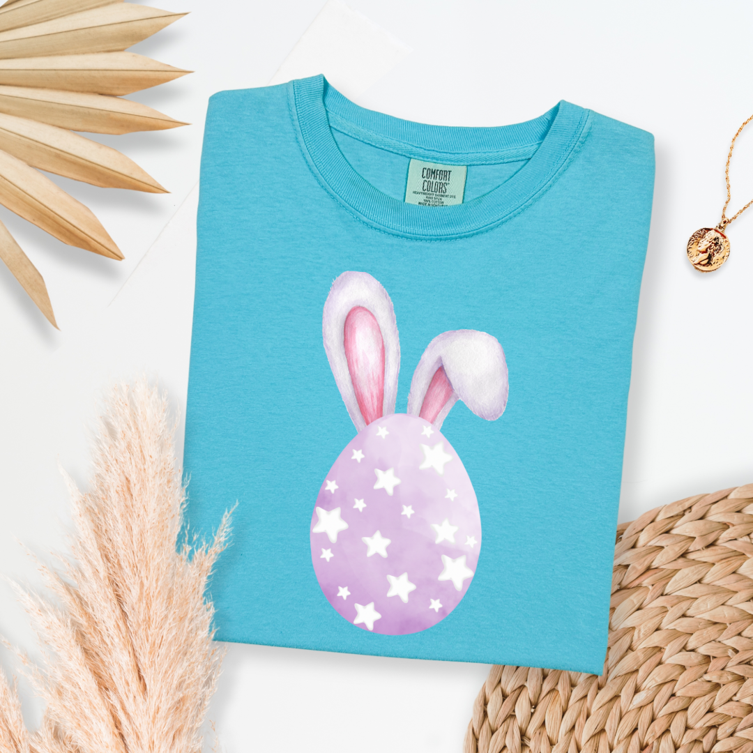 Customized adult comfort colors lagoon blue graphic tee with purple watercolor egg with white stars matching crewneck and hoodies available in youth and adult sizes