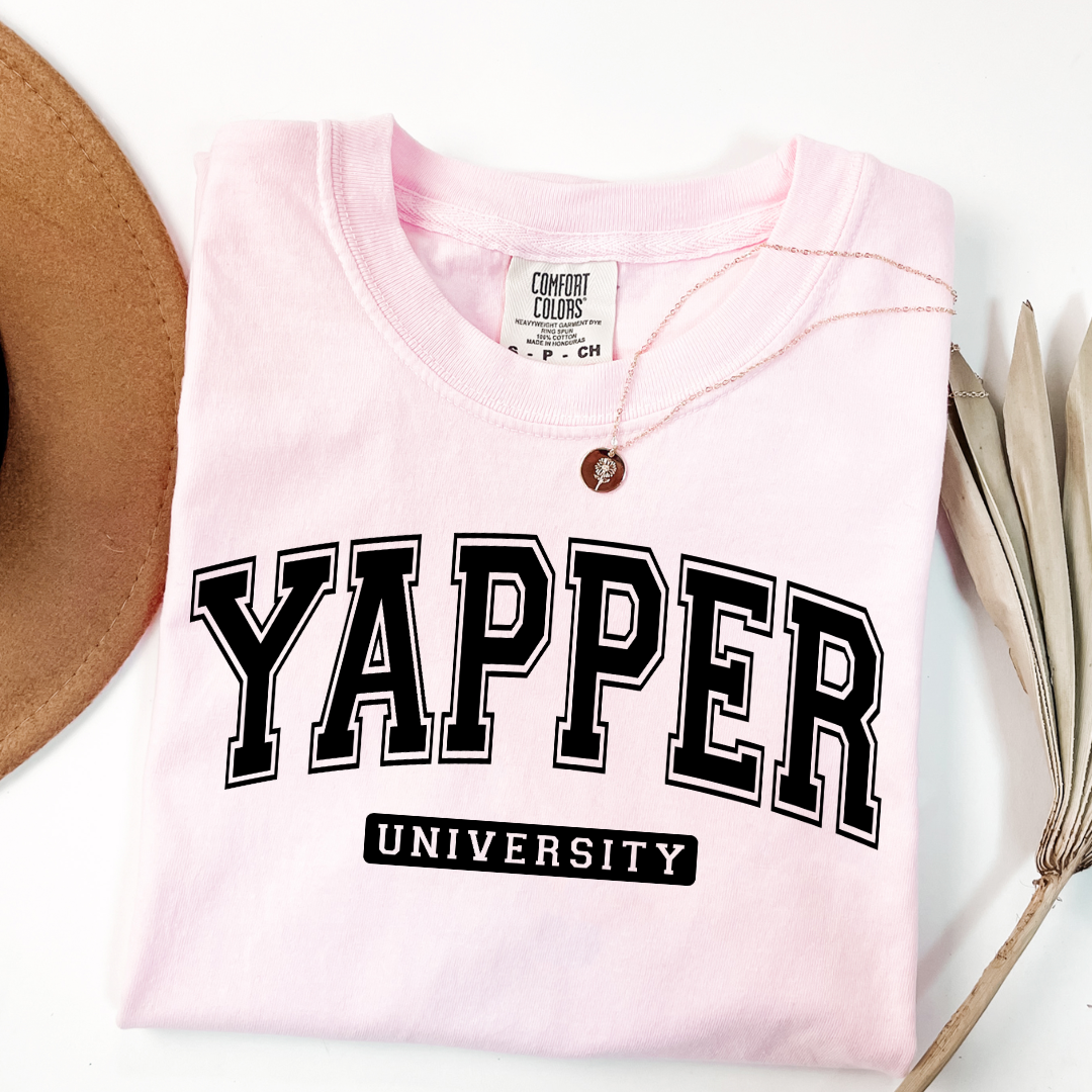 Customized adult comfort colors Blossom Pink Graphic tee with black varsity lettering yapper university Matching hoodies and crewnecks in adult and youth sizes available.