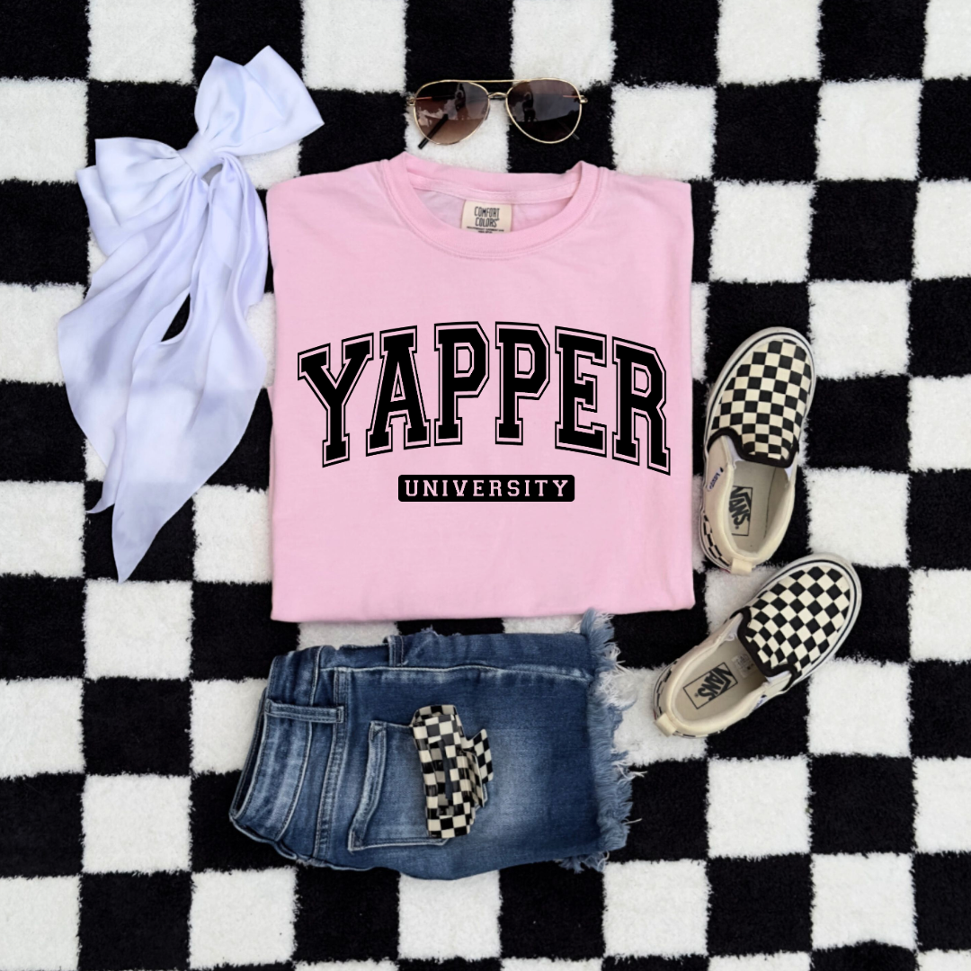 Customized Youth comfort colors Blossom Pink flat lay Graphic tee with black varsity lettering yapper university Matching hoodies and crewnecks in adult and youth sizes available.