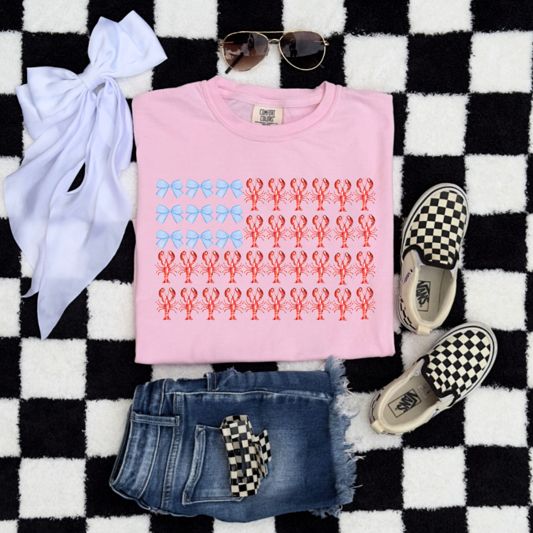 Customized comfort colors Blossom Pink Youth Graphic tee with American Flag made of blue bows and red lobsters. Perfect for 4th of July Ranging in sizes youth Small to adult 4X also comes in matching hoodies and crewnecks.