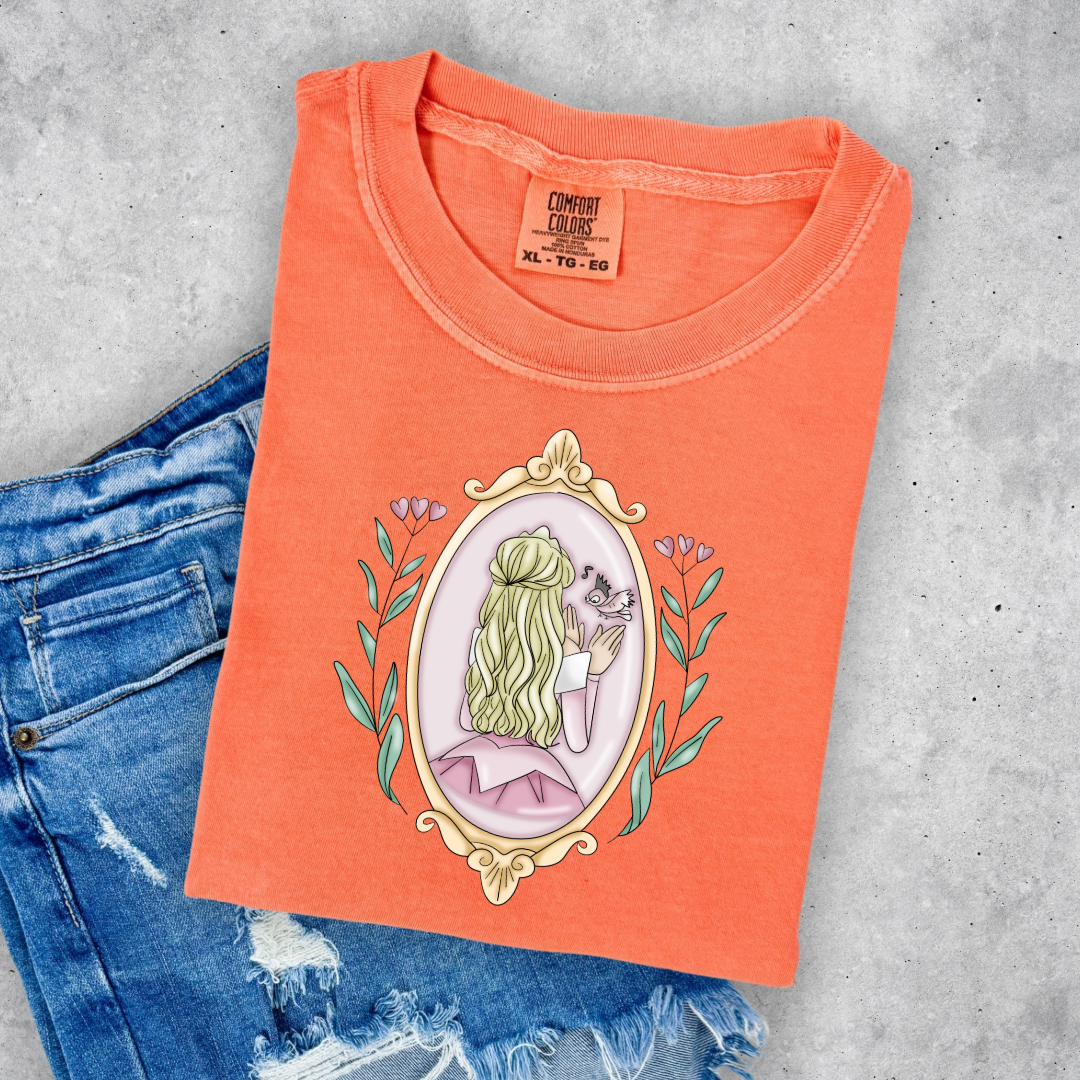 Customized comfort colors melon orange Graphic tee Disney Princess sleeping beauty/Aurora back silhouette in a gold mirror with flower vines up the side. Designs are available in Adult and youth graphic tees as well as youth and adult crewnecks and adult hoodies. 
