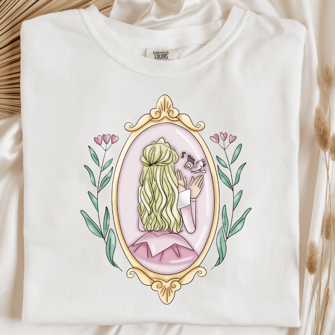 Customized comfort colors white Graphic tee Disney Princess sleeping beauty/Aurora back silhouette in a gold mirror with flower vines up the side. Designs are available in Adult and youth graphic tees as well as youth and adult crewnecks and adult hoodies. 
