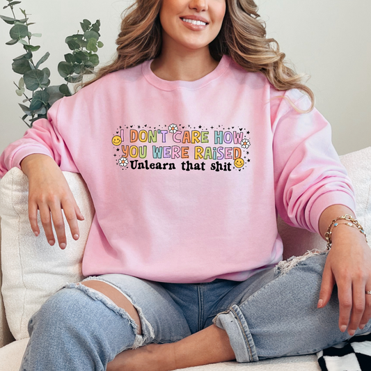 Customized adult Light Pink Crewneck " I don't care how you were raised" rainbow capital letters Unlearn that shit Black bubble letters. Smiley faces and flowers around. good for pride month matching adult Graphic Tees Available. 