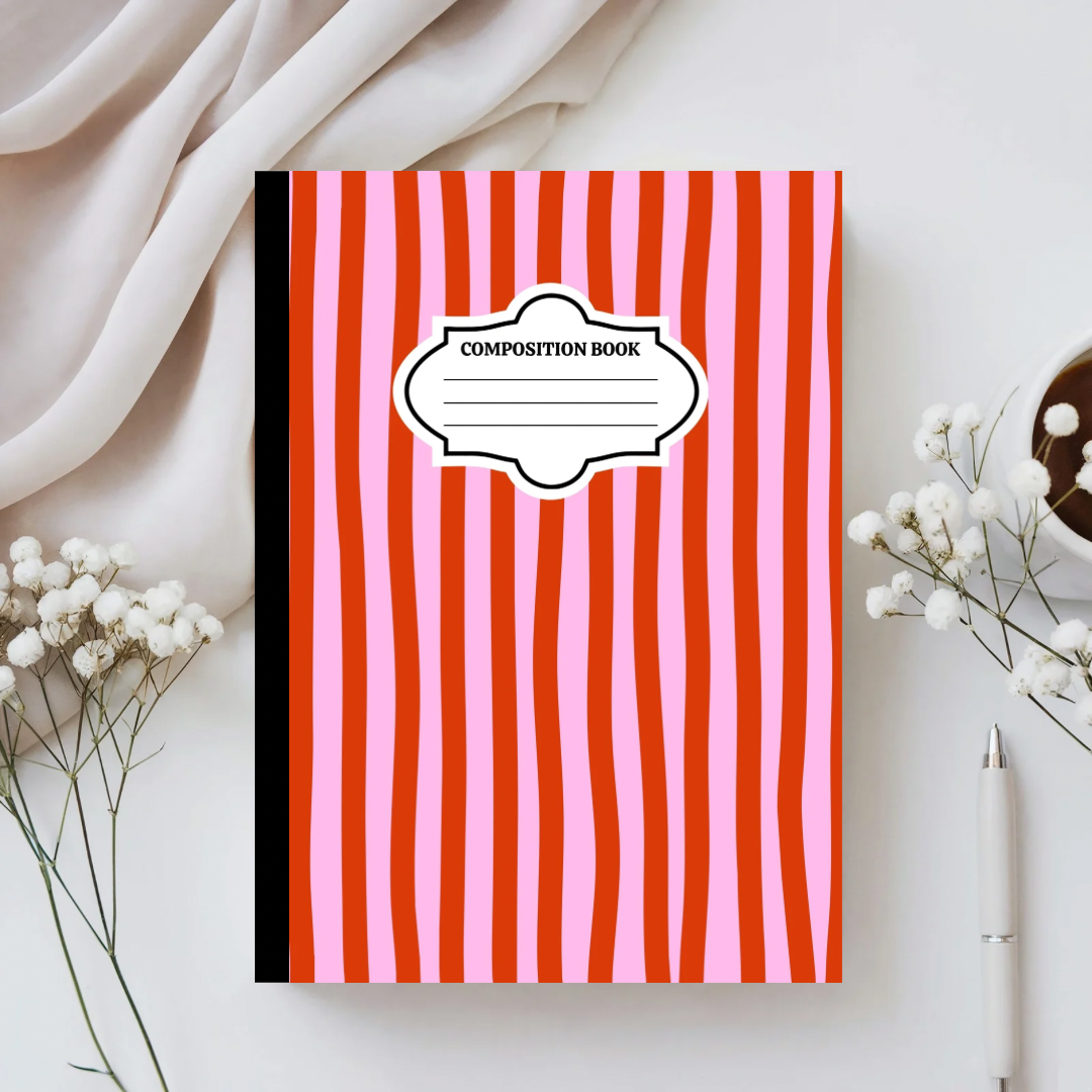 Composition book with red and pink striped cover on a white surface with flowers and a pen.
