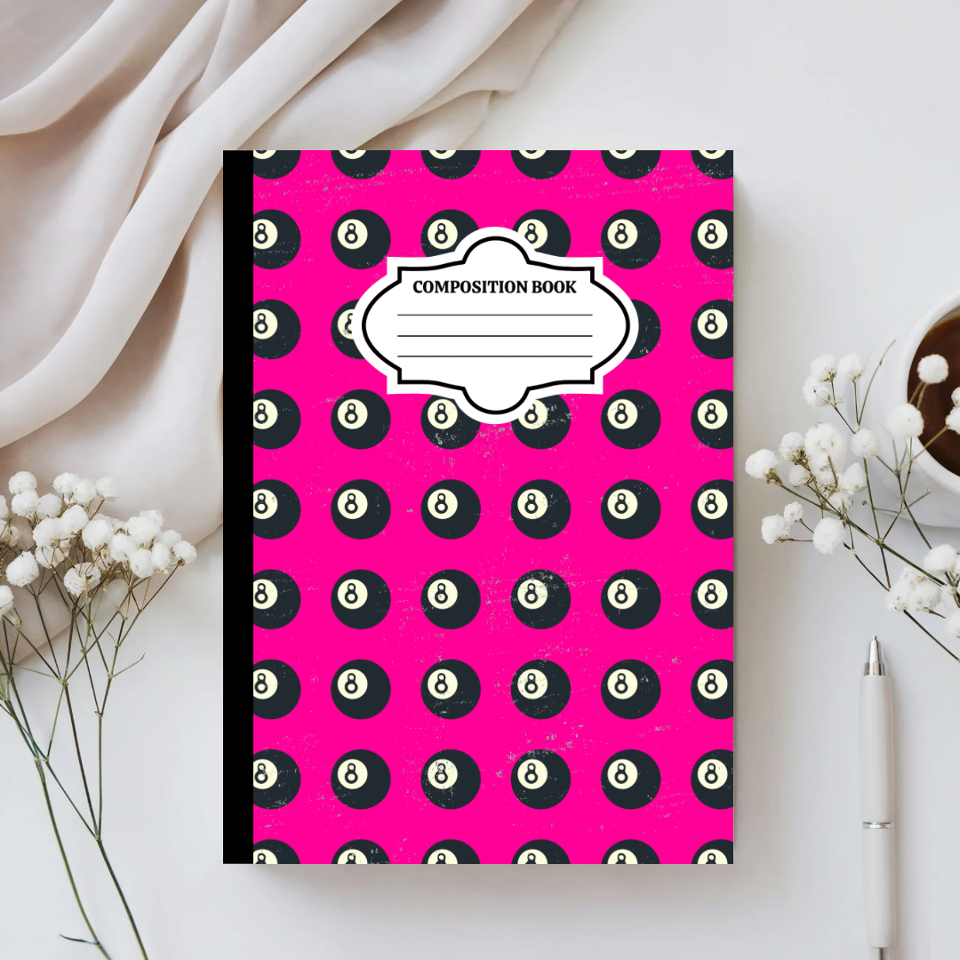 Composition book with pool ball pattern on a white surface with flowers and a pen.