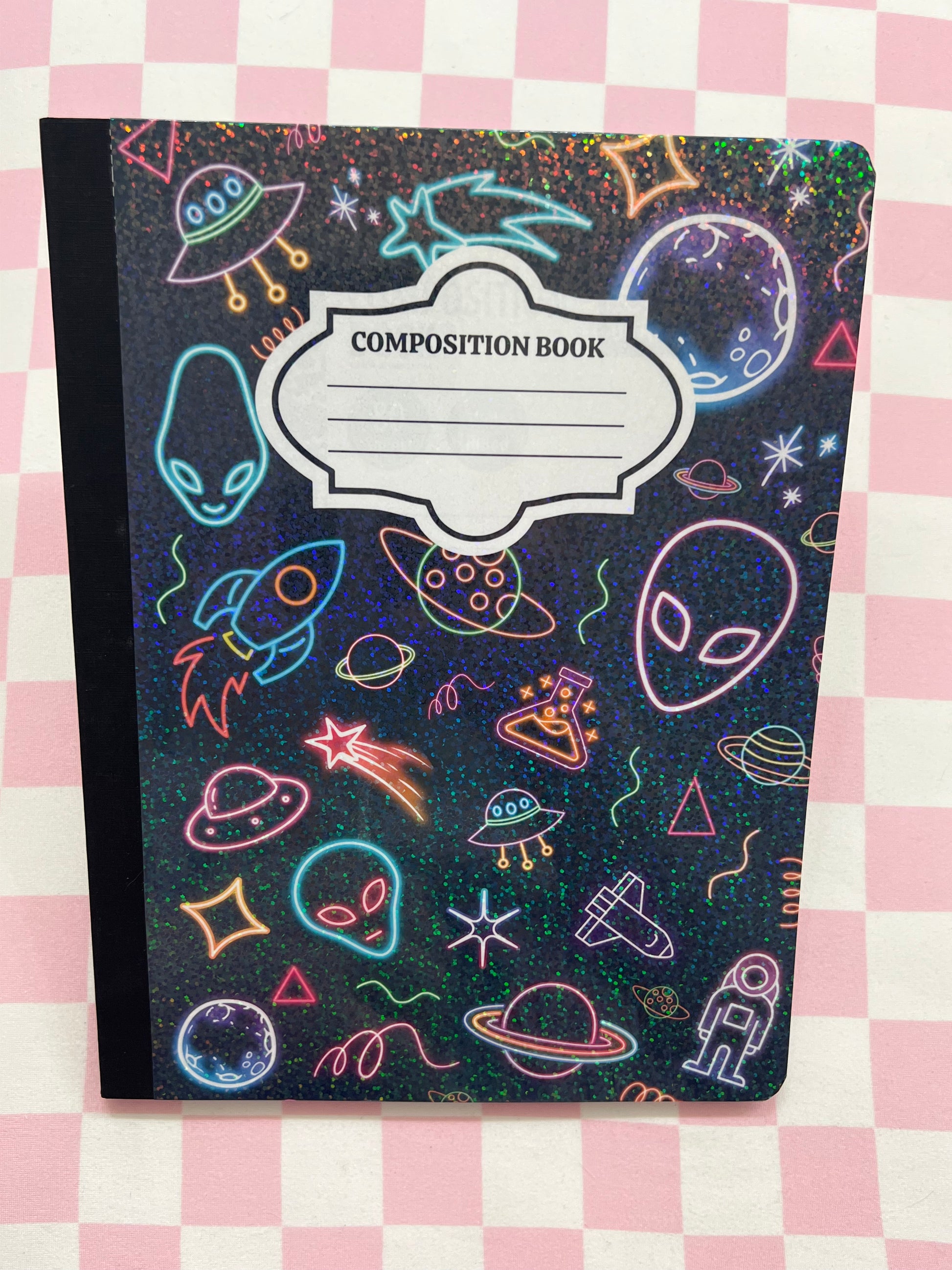 Composition book with space-themed design on a checkered background