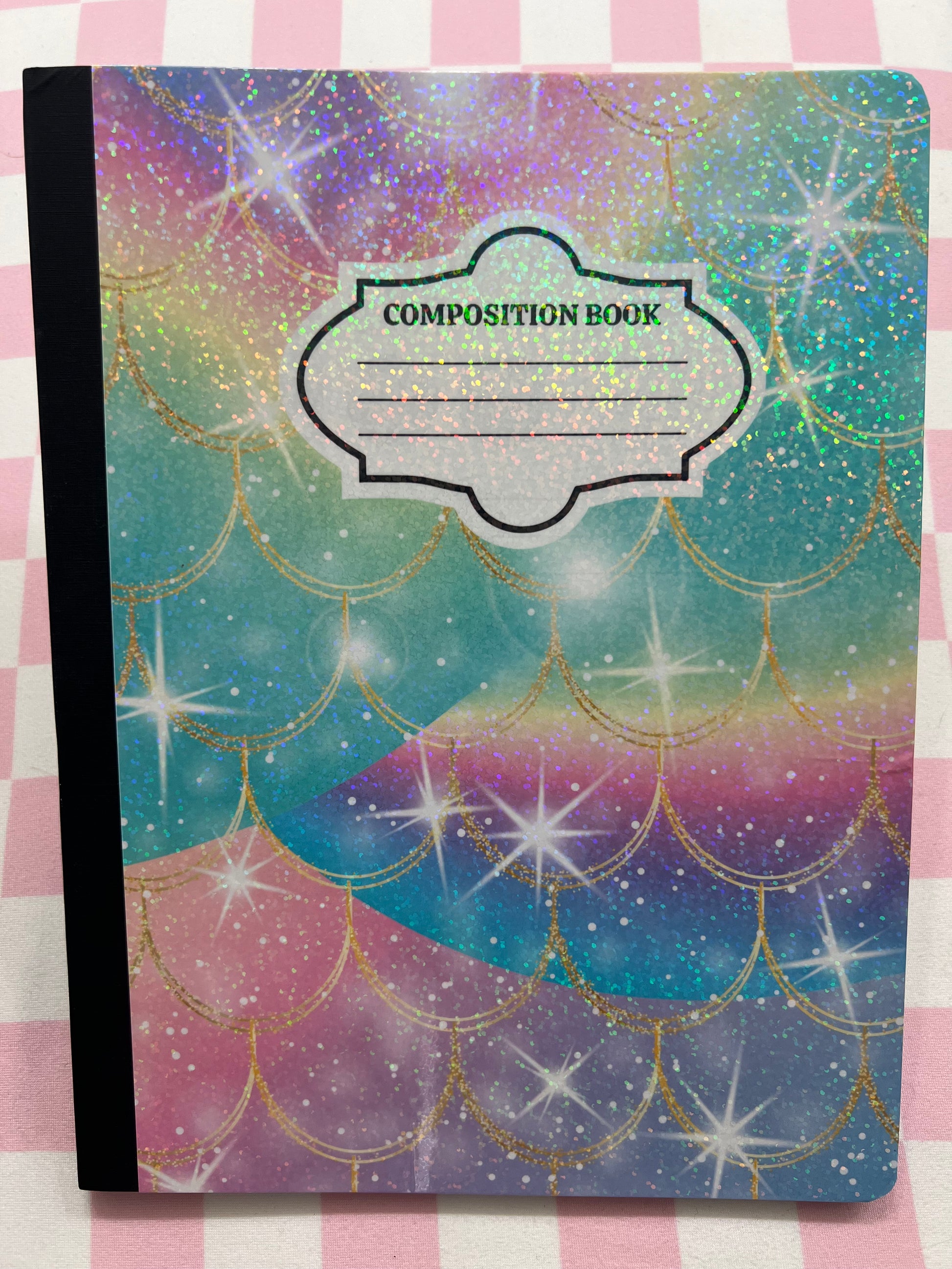 Composition book with mermaid scale design on a checkered background