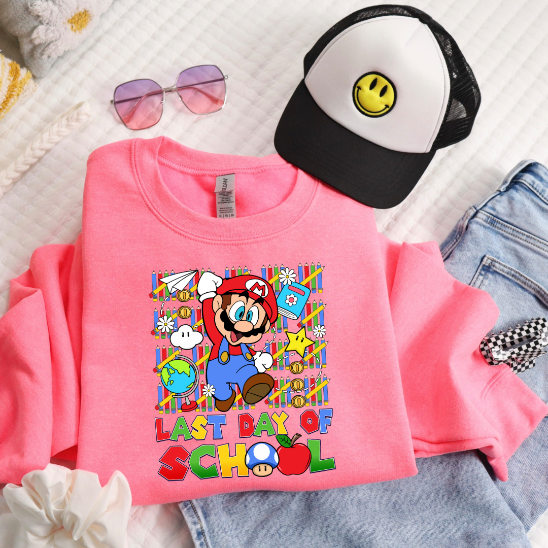 Customized Youth hot pink flat lay comfort colors graphic tee. Last day of school Mario Nintendo world bubble letter font. With clouds Matching graphic tees available in youth sizing