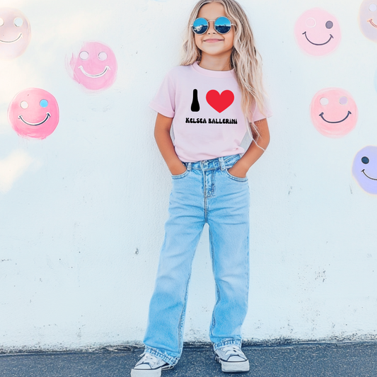 Customized youth comfort colors Blossom Pink graphic tee with black groovy bubble letters I red heart Kelsea Ballerini. Matching crewneck and hoodies available in youth and adult sizing.