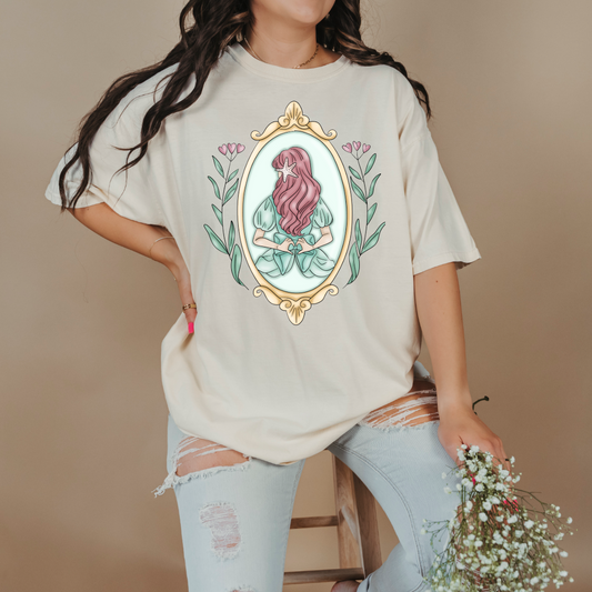 Customized comfort colors Ivory Graphic tee Disney Princess Ariel back silhouette in a gold mirror with flower vines up the side. Designs are available in Adult and youth graphic tees as well as youth and adult crewnecks and adult hoodies. 