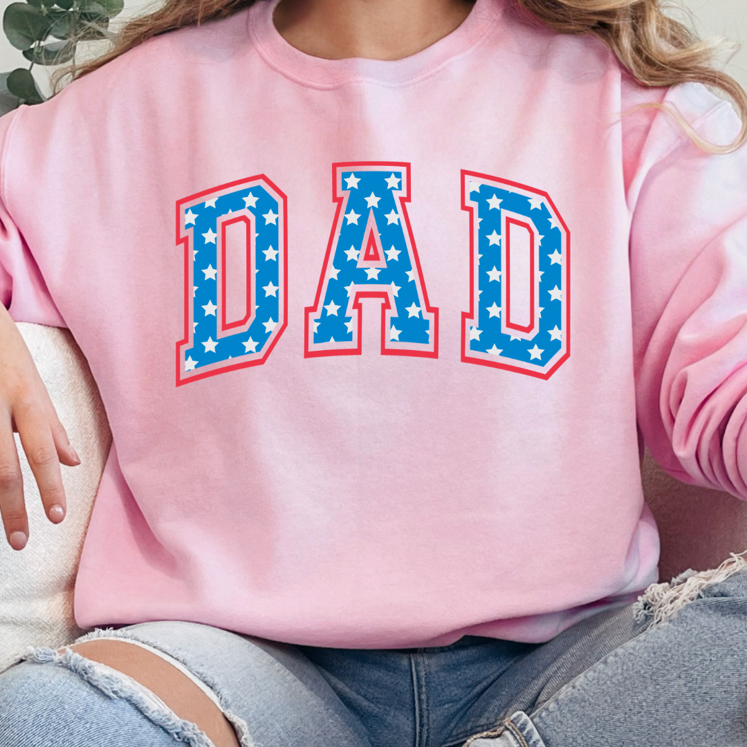 Customized adult Light Pink Crewneck  with Seasonal 4th of July University style Font DAD blue with white stars outlined un red , This style is available in adult  Graphic Tees as well as adult crewnecks and hoodies .Available In DAD, MAMA and MINI. 