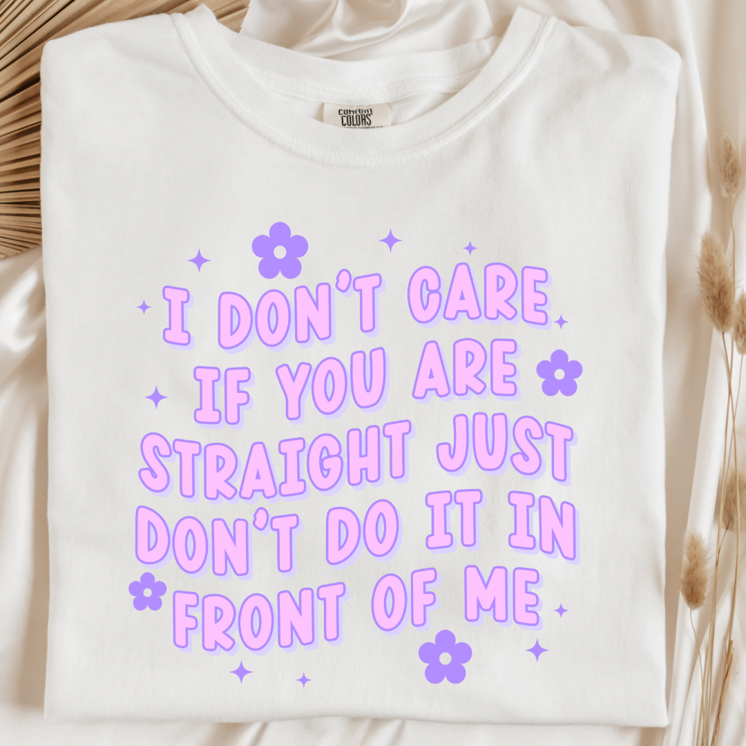 Customized Adult Comfort Colors white Graphic Tee Quoted " I don't care if you're straight just don't do it in front of me.  Purple bubble letters with flowers spread out Matching Adult Crewnecks available Perfect for Pride.