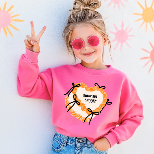 Youth Safety Pink Crewneck with coquette halloween themed cakes Sweet but spooky on the top with icing boarders and bows. This design is available in sizes ranging From youth small through adult 4X. 