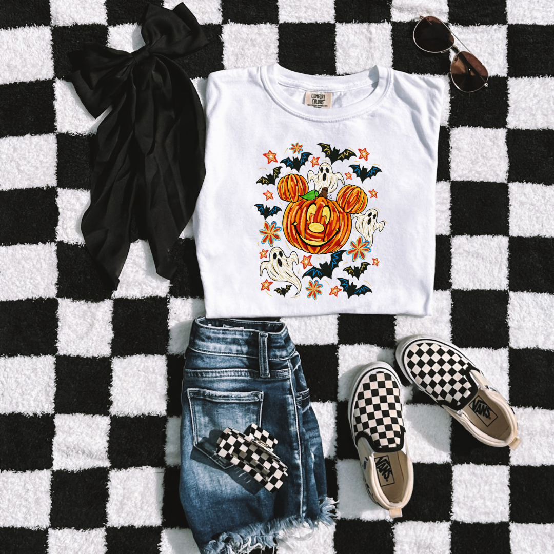 Youth Comfort Colors White Graphic Tee Folded Flat lay with Dimensional Mickey Mouse pumpkin head with ghosts, bows and bats. This Design Is available in Youth sizes Small through XL. Minnie Mouse available as well 