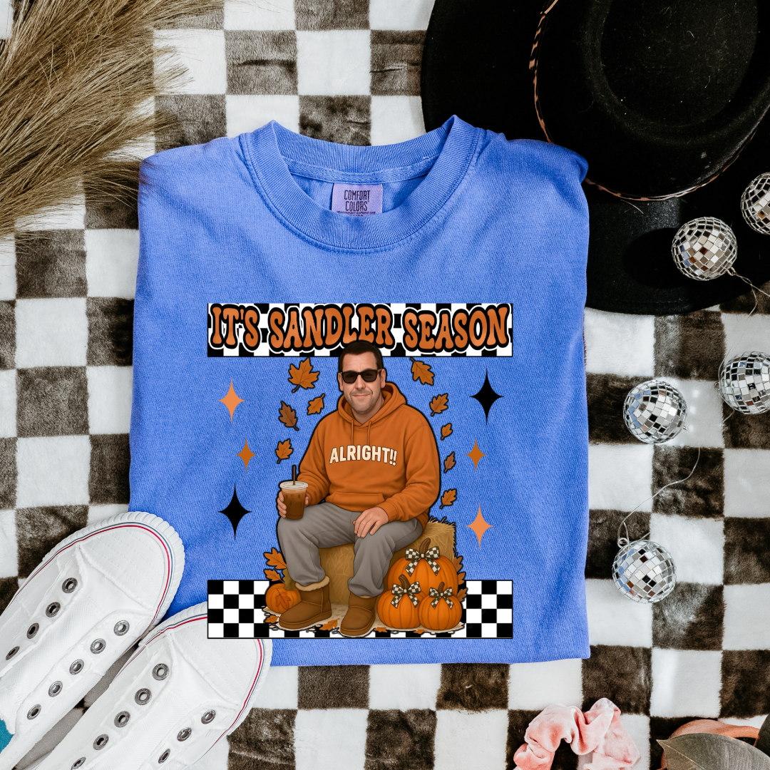 Comfort Colors Flo Blue  Adult Graphic Tee with Adam Sandler on the front sitting on a hay bale stack with a coffee in hand wearing UGGS and checker board its Sandler season. Design available in graphic tees as well in Adult sizing ranging from Small to 4X.