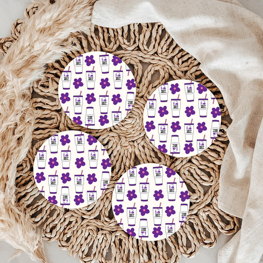 Patterned coasters with purple flowers and white backgrounds on a textured surface.