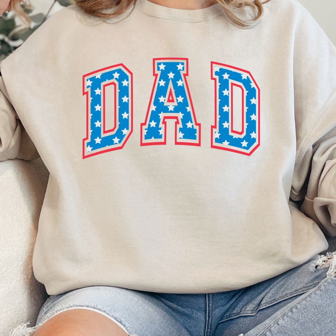 Customized adult Beige Crewneck  with Seasonal 4th of July University style Font DAD blue with white stars outlined un red , This style is available in adult  Graphic Tees as well as adult crewnecks and hoodies .Available In DAD, MAMA and MINI. 